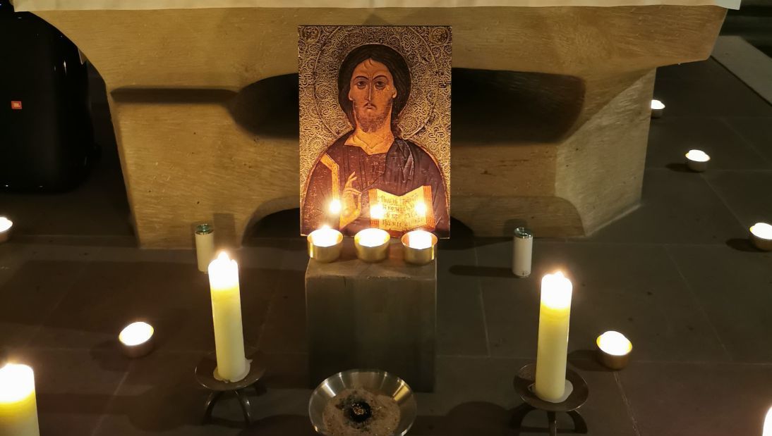 brennende Kerzen vor einem Jesusbild