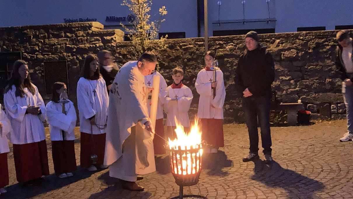 Pfarrer Mattäi entzündet die Osterkerze am Osterfeuer am Platz vor der Rasdorfer Stiftskirche