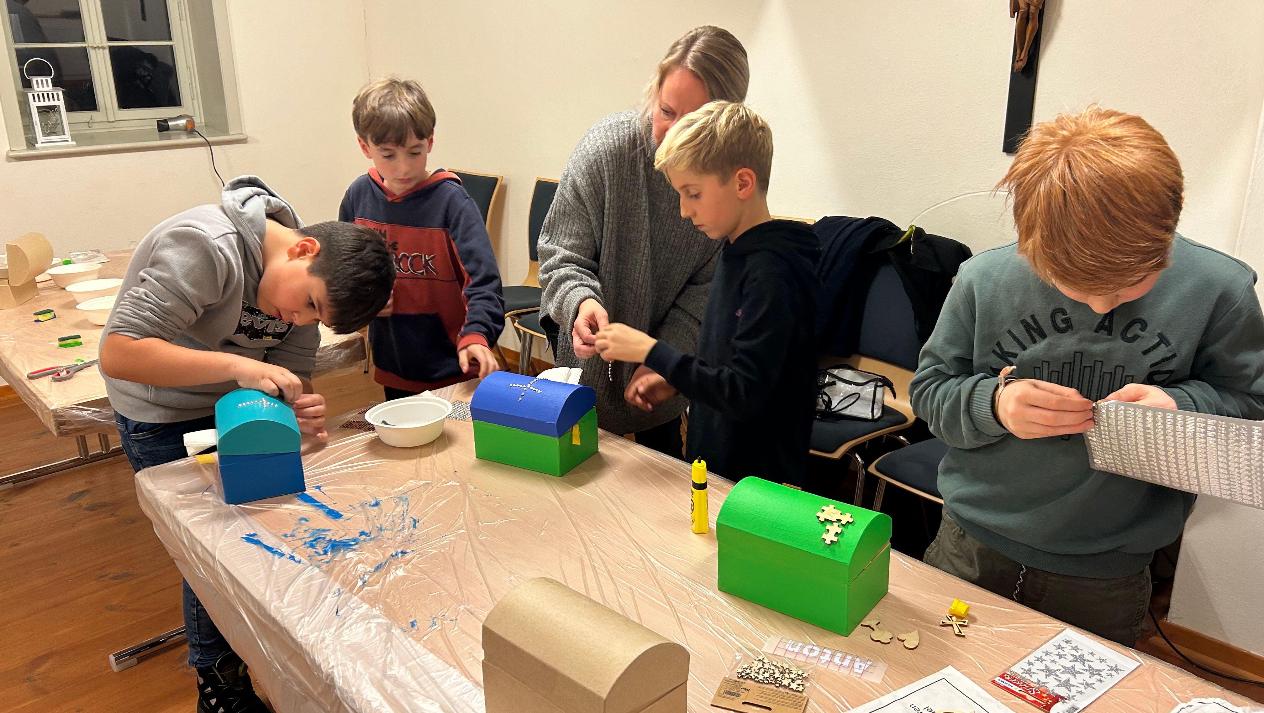 Erstkommunionkinder mit ihren Eltern beim Basteln der Schatztruhe