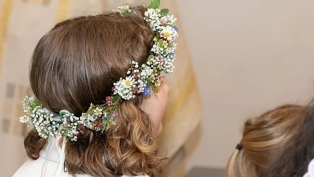 Erstkommunionkind mit Blumenschmuck im Haar